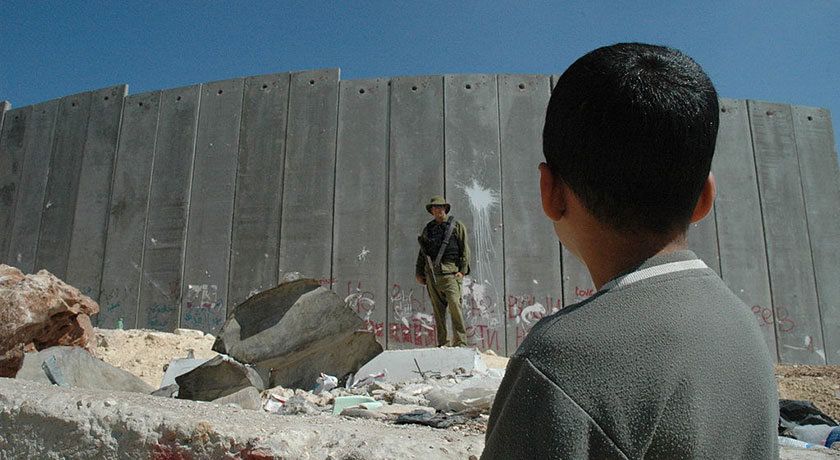 Boy and soldier in front of Israeli wall credit Justin McIntosh news banner